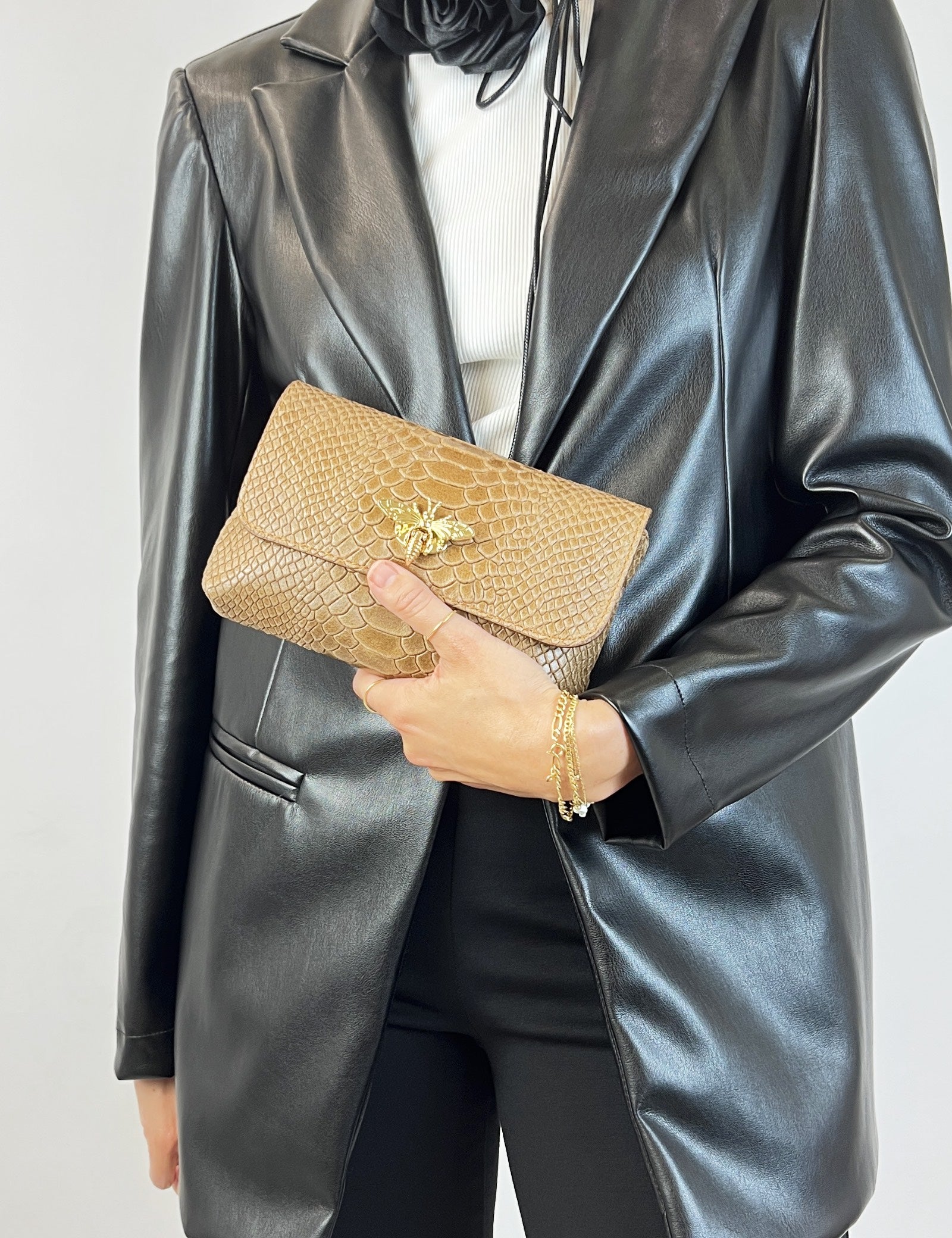 Borsa modello MARTA in pelle effetto pitonato con chiusura dorata a forma di ape, vista frontale, tenuta a mano